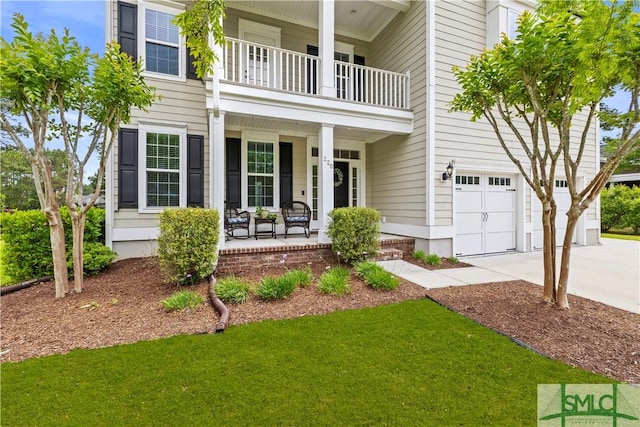 exterior space with an attached garage, a front yard, concrete driveway, a balcony, and covered porch