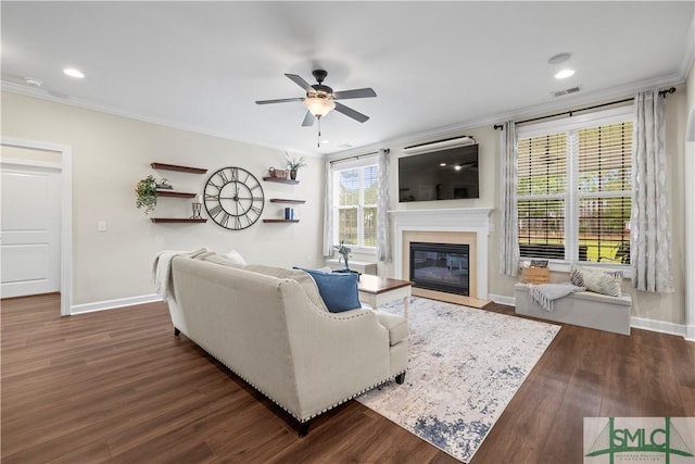 living room with ornamental molding, baseboards, ceiling fan, dark wood-style floors, and a fireplace with flush hearth