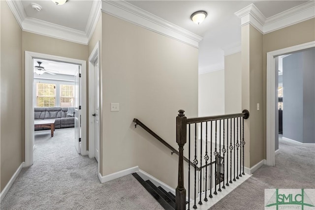 hallway with carpet floors, ornamental molding, baseboards, and an upstairs landing
