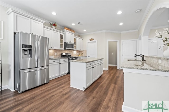 kitchen featuring a sink, stainless steel appliances, white cabinetry, tasteful backsplash, and ornamental molding