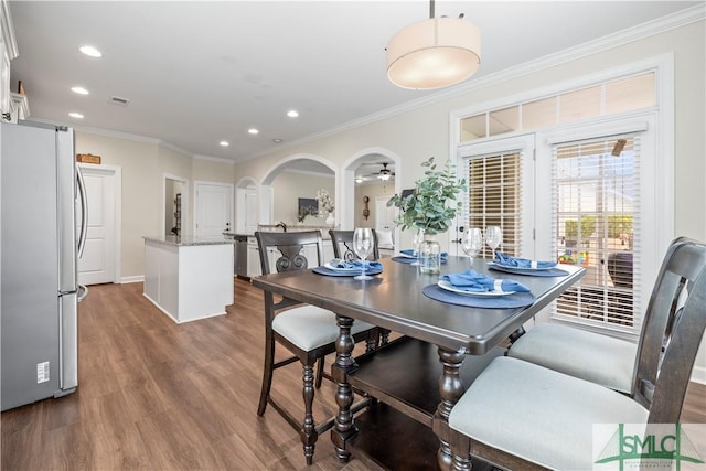 dining area featuring crown molding, visible vents, wood finished floors, recessed lighting, and arched walkways