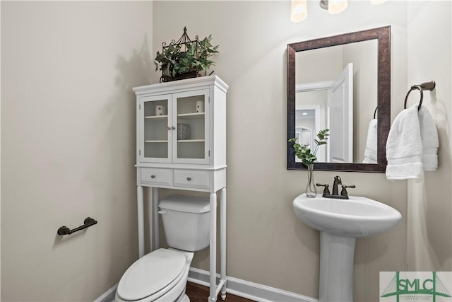 half bathroom featuring a sink, baseboards, and toilet