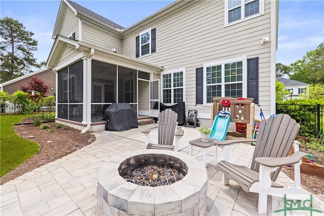 back of property featuring fence, a patio area, a sunroom, and an outdoor fire pit