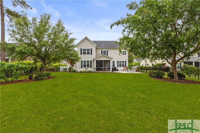 rear view of house with a lawn, a patio, fence, and a sunroom