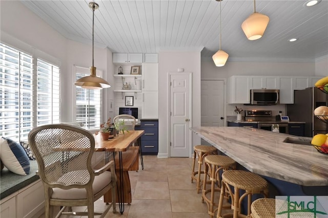 kitchen with pendant lighting, appliances with stainless steel finishes, a breakfast bar, and ornamental molding