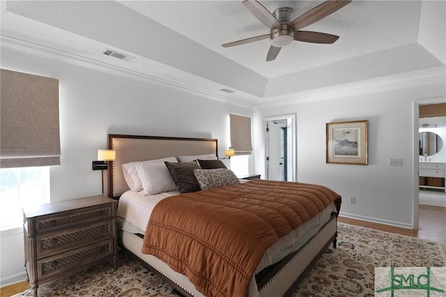 bedroom featuring visible vents, a raised ceiling, crown molding, and wood finished floors