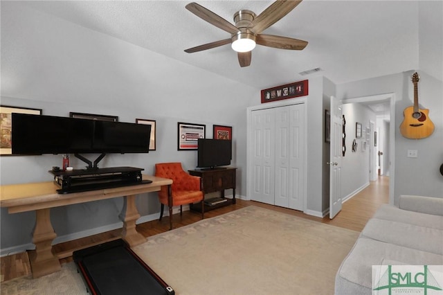 living area with a ceiling fan, visible vents, vaulted ceiling, wood finished floors, and baseboards