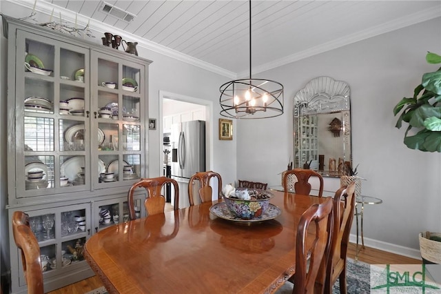 dining room with crown molding, visible vents, wood finished floors, and a notable chandelier