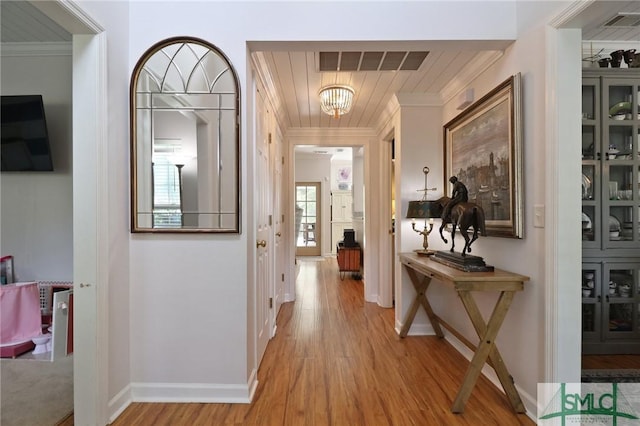 hallway featuring visible vents, ornamental molding, light wood-style flooring, and a notable chandelier