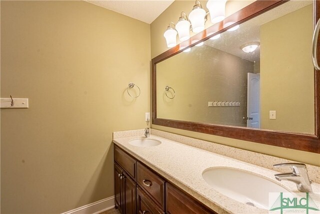 bathroom featuring a sink, baseboards, and double vanity
