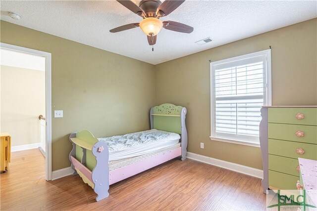 bedroom with visible vents, multiple windows, and wood finished floors