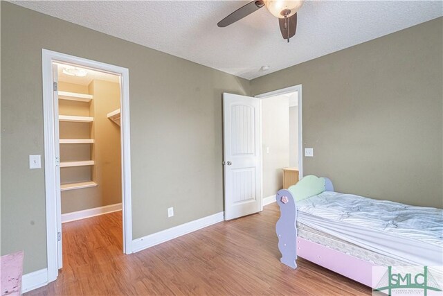 bedroom with baseboards, ceiling fan, a textured ceiling, and wood finished floors