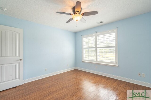 spare room featuring visible vents, a textured ceiling, ceiling fan, and wood finished floors