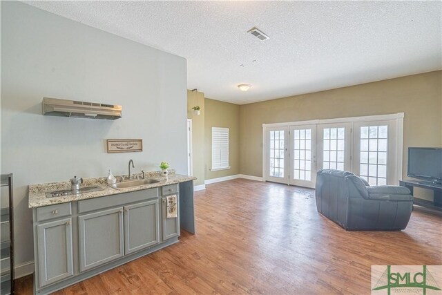 kitchen with a sink, light wood-style floors, gray cabinetry, and visible vents