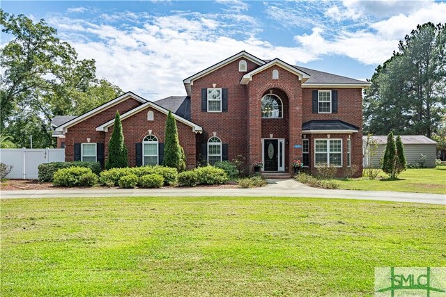 view of front of property with fence, a front lawn, and brick siding