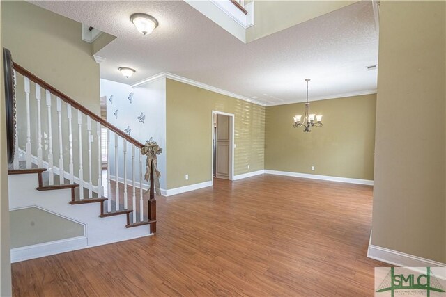 interior space with wood finished floors, baseboards, a notable chandelier, ornamental molding, and stairs