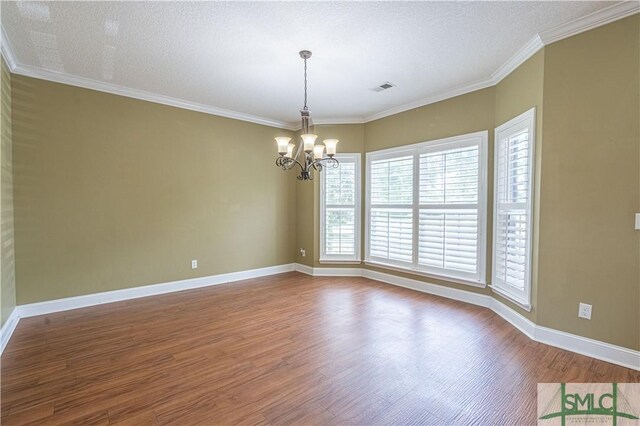 spare room featuring visible vents, wood finished floors, baseboards, an inviting chandelier, and ornamental molding