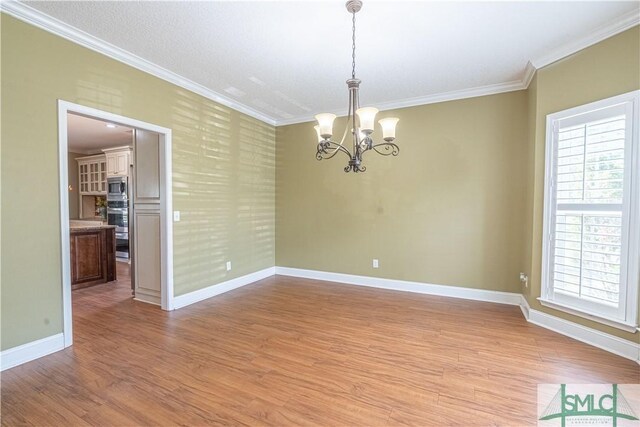 unfurnished room featuring crown molding, baseboards, and an inviting chandelier