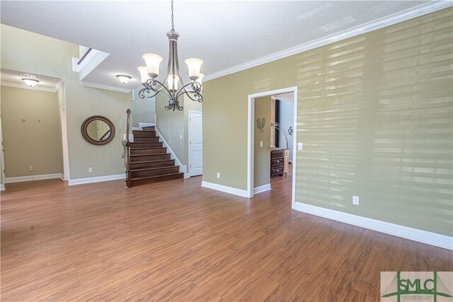 unfurnished living room featuring baseboards, a chandelier, ornamental molding, and light wood-style flooring