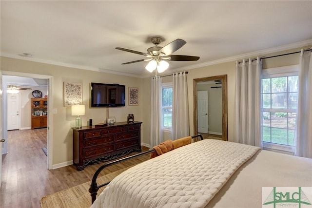 bedroom featuring crown molding, baseboards, multiple windows, and wood finished floors