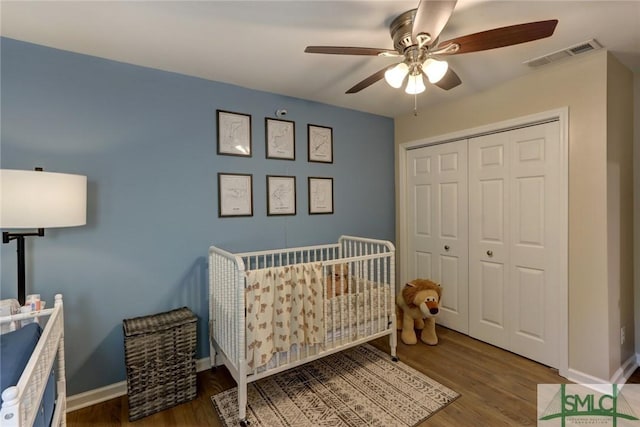 bedroom featuring visible vents, a closet, wood finished floors, baseboards, and a ceiling fan