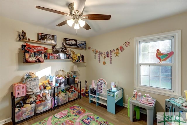 recreation room with baseboards, a ceiling fan, and wood finished floors