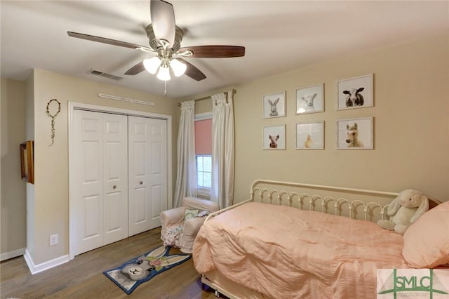 bedroom featuring ceiling fan, visible vents, wood finished floors, baseboards, and a closet