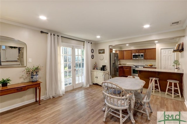 dining area featuring crown molding, light wood-style flooring, and visible vents