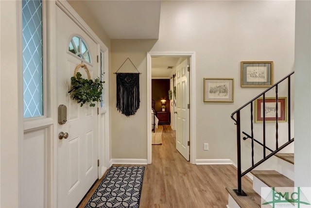 foyer with baseboards, stairway, and light wood-type flooring