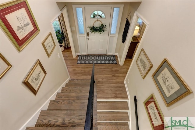 foyer entrance with baseboards, stairs, and wood finished floors
