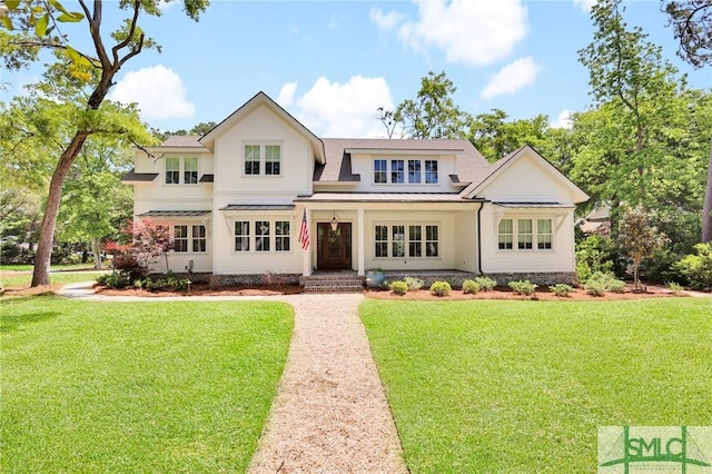 view of front of house featuring metal roof, covered porch, a front yard, and a standing seam roof