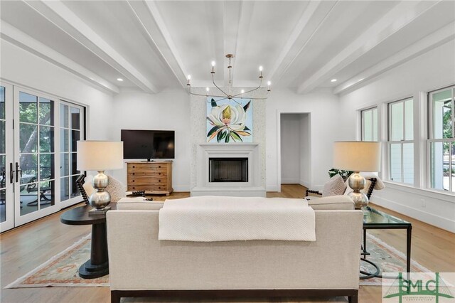 living area with beamed ceiling, a wealth of natural light, and light wood-style flooring