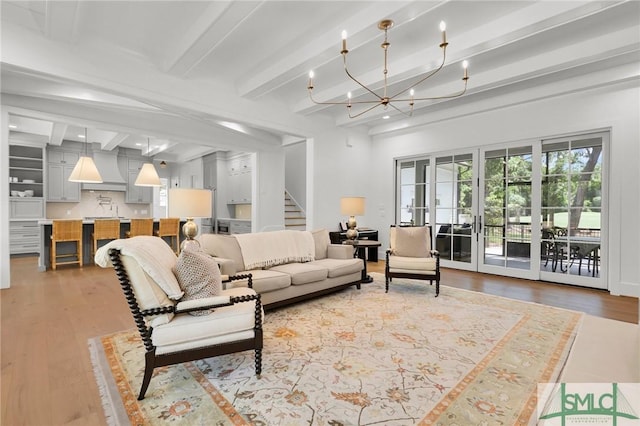 living room with an inviting chandelier, stairs, beam ceiling, and wood finished floors