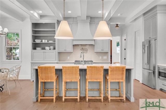 kitchen featuring light countertops, high end fridge, beam ceiling, and premium range hood