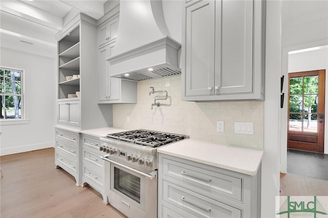 kitchen with a healthy amount of sunlight, light countertops, custom exhaust hood, and high end range