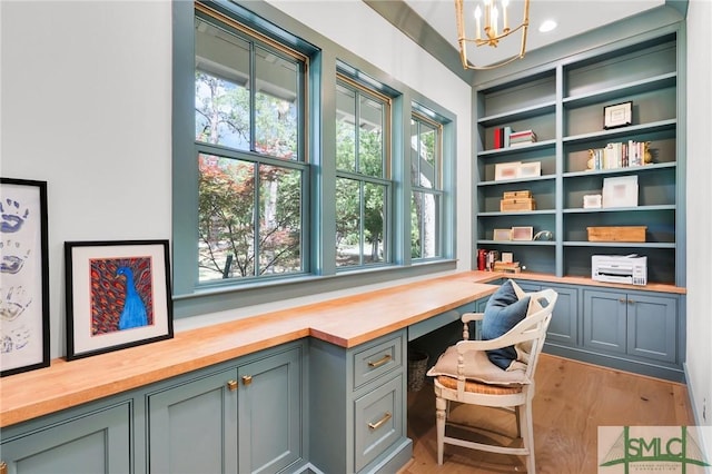 office area featuring a healthy amount of sunlight, light wood finished floors, built in desk, and a chandelier