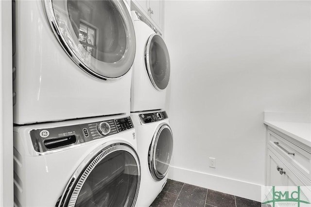laundry room with baseboards, cabinet space, and stacked washer / dryer