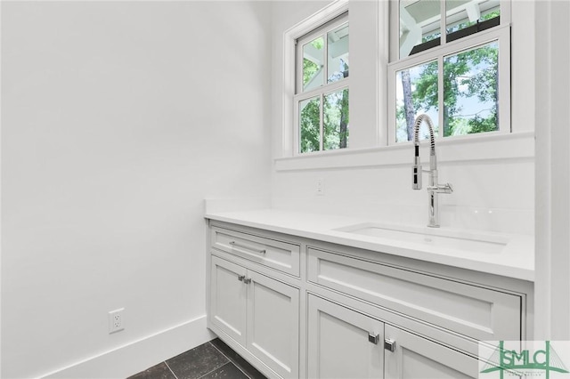 bar featuring a sink, baseboards, and dark tile patterned floors
