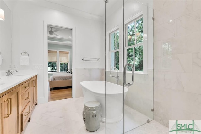 full bathroom featuring a freestanding bath, a sink, double vanity, tile walls, and ensuite bathroom