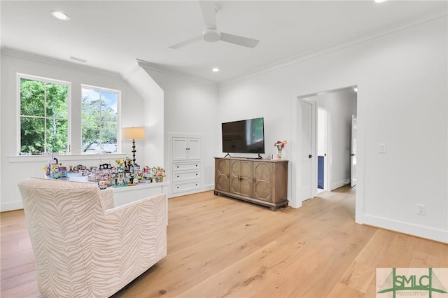 living room featuring light wood-style floors, ornamental molding, a ceiling fan, and visible vents