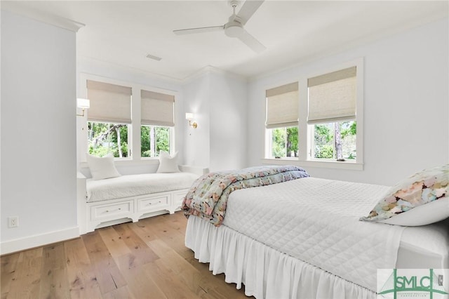bedroom featuring ceiling fan, visible vents, crown molding, baseboards, and light wood-style flooring