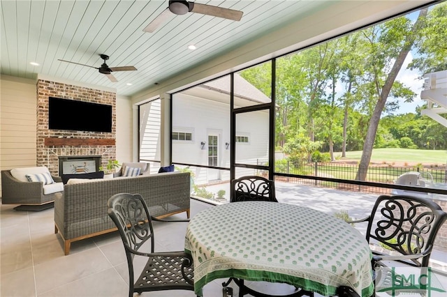 sunroom featuring outdoor dining area, an outdoor living space with a fireplace, and ceiling fan