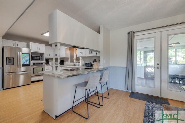 178 Country Way, Springfield, GA 31329 - kitchen with wainscoting, light wood finished floors, stainless steel appliances, white cabinetry, and a peninsula