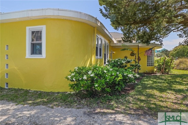 view of side of home featuring stucco siding and a yard