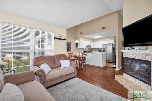 living area with visible vents, dark wood-style flooring, and a multi sided fireplace