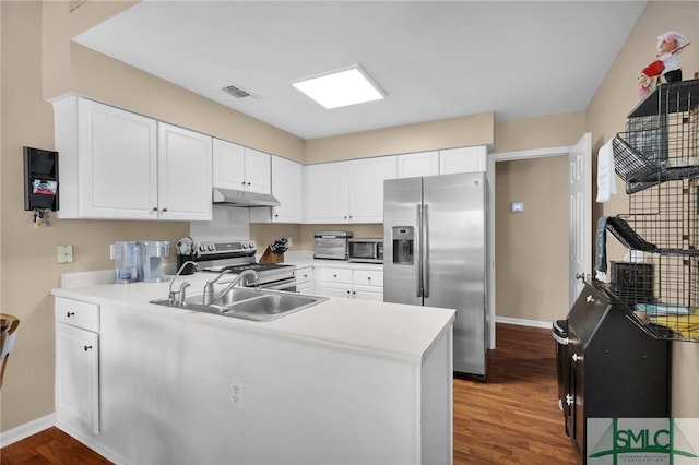 kitchen featuring appliances with stainless steel finishes, wood finished floors, a sink, a peninsula, and under cabinet range hood