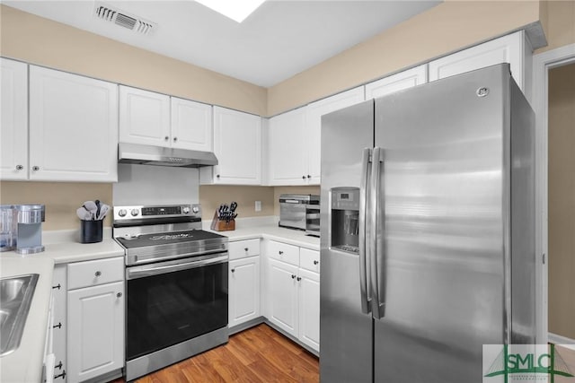 kitchen with light countertops, stainless steel appliances, white cabinetry, under cabinet range hood, and visible vents