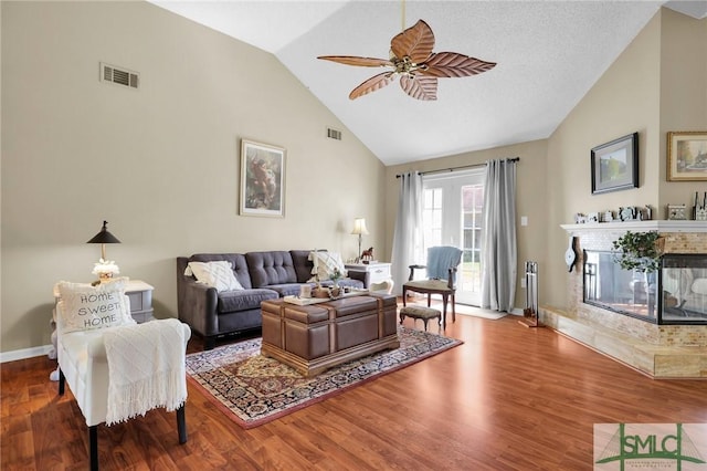 living area featuring visible vents, wood finished floors, baseboards, ceiling fan, and a tiled fireplace
