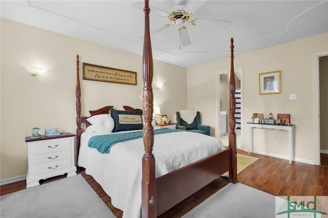 bedroom featuring baseboards, ceiling fan, wood finished floors, and ensuite bath