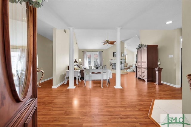 interior space featuring baseboards, a ceiling fan, vaulted ceiling, and light wood-style flooring